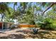 Spacious backyard with mature trees and a seating area, perfect for outdoor relaxation and entertainment at 1516 Santa Anna Dr, Dunedin, FL 34698