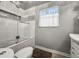 Bathroom featuring a bathtub/shower combination with glass doors, tile accents and a window at 1516 Santa Anna Dr, Dunedin, FL 34698