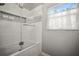 Bright bathroom featuring a shower over tub with decorative tile and natural light through a window at 1516 Santa Anna Dr, Dunedin, FL 34698