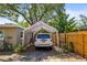 View of car parked under a tent-style carport next to the house and wood fence at 1516 Santa Anna Dr, Dunedin, FL 34698