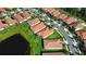 Aerial view of a neighborhood with a pond and red tile roofs with green lawns at 16913 Anchor Root St, Wimauma, FL 33598
