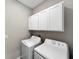 Bright laundry room with front loading washer and dryer, and white overhead cabinets at 16913 Anchor Root St, Wimauma, FL 33598