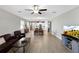 Open-concept living space with wood floors, ceiling fan, a view of the kitchen and dining areas at 16913 Anchor Root St, Wimauma, FL 33598
