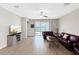 Spacious living room with wood-look flooring, comfortable seating, and a sliding glass door to the outside at 16913 Anchor Root St, Wimauma, FL 33598