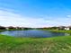 Picturesque pond with green lawn surround by homes in the neighborhood at 16913 Anchor Root St, Wimauma, FL 33598