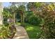 Landscaped backyard walkway with lush plants, grass and trees leading to the pool at 1799 Dixie Hwy, Tarpon Springs, FL 34689
