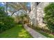 Landscaped backyard walkway with lush plants, grass and trees leading to the house at 1799 Dixie Hwy, Tarpon Springs, FL 34689