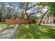 Landscaped front yard featuring a well-maintained lawn and a charming wood fence at 1799 Dixie Hwy, Tarpon Springs, FL 34689