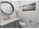 Powder room features a round mirror with gray vanity and seaside artwork at 19029 Us Highway 19 N # 5-16, Clearwater, FL 33764