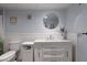 A newly renovated bathroom with a round mirror, white vanity, white wainscotting and light blue walls at 19029 Us Highway 19 N # 5-16, Clearwater, FL 33764