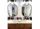 Double vanity bathroom with wood cabinets, granite counters, and decorative mirrors at 19420 Haskell Pl, Land O Lakes, FL 34638