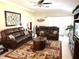 Cozy living room featuring comfortable leather furniture, ceiling fan, and large decorative wall art at 19420 Haskell Pl, Land O Lakes, FL 34638