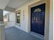 Close-up of the front door with navy blue color, house number, and a charming covered porch at 21033 Market St, Dade City, FL 33523