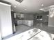 Modern kitchen featuring white cabinets, stainless steel appliances, and an open view to the living area at 21033 Market St, Dade City, FL 33523