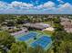 Scenic aerial shot of tennis courts and pool area surrounded by mature trees, showing off the community amenities at 2614 Hawk Roost Ct, Holiday, FL 34691