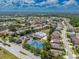 Expansive aerial view of the community featuring a pool, tennis courts, and lush landscaping on a sunny day at 2614 Hawk Roost Ct, Holiday, FL 34691