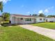 Home with a carport and long driveway, complemented by green grass and mature trees on a sunny day at 302 Patty Dr, Oldsmar, FL 34677
