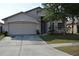 Two-story house with a beige exterior, attached two-car garage, and well-maintained lawn at 30742 Birdhouse Dr, Wesley Chapel, FL 33545