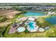 An aerial view features a community pool, splash pad, playground, and nearby pond in a residential area at 33524 Elm Hill Br, Wesley Chapel, FL 33545