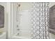 Clean bathroom showcasing a white tiled shower-tub, patterned curtain, and neutral towels at 33524 Elm Hill Br, Wesley Chapel, FL 33545