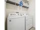 Bright laundry room featuring a Whirlpool washer and dryer, plus extra storage shelves with decorative baskets at 33524 Elm Hill Br, Wesley Chapel, FL 33545