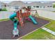 Fun backyard playground featuring a slide, swings, and playhouse on a mulch base at 33524 Elm Hill Br, Wesley Chapel, FL 33545