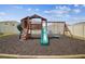 Wooden playset with a slide, climbing wall, and swings, set on mulch with a log border at 33524 Elm Hill Br, Wesley Chapel, FL 33545
