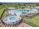Aerial view of a luxurious community pool with multiple pools, a hot tub, lounge chairs, and palm trees at 33524 Elm Hill Br, Wesley Chapel, FL 33545