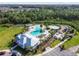 Aerial view of a community pool and splash pad with palm trees, ample seating, and a clubhouse at 33524 Elm Hill Br, Wesley Chapel, FL 33545