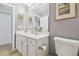 Bathroom with a large mirror, white cabinets, toilet, and neutral decor at 3737 Gaviota Dr, Sun City Center, FL 33573