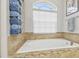 Bright soaking tub with tile surround next to window and stack of fresh towels at 3737 Gaviota Dr, Sun City Center, FL 33573