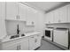 Well-equipped laundry room with white cabinetry, countertop, sink, and modern washer and dryer units at 403 E Davis Blvd, Tampa, FL 33606