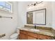 Updated bathroom with granite counters, dark wood cabinets, vanity lighting, framed mirror, toilet, and glass shower at 407 S Fremont Ave # B, Tampa, FL 33606