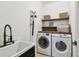 Functional laundry room equipped with sink, washer, dryer, and shelving for organized convenience at 407 S Fremont Ave # B, Tampa, FL 33606