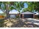 Charming single-story home featuring brick accents, mature trees, and an attached two-car garage at 502 Timber Bay E Cir, Oldsmar, FL 34677