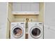 Laundry room featuring a white washer and dryer with overhead storage cabinets and white bi-fold doors at 502 Timber Bay E Cir, Oldsmar, FL 34677
