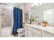 Bathroom with a shower-tub combo with blue shower curtain, quartz countertops and white cabinets at 5090 Caravel Pt, Land O Lakes, FL 34638