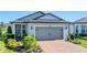 Attractive home featuring a brick driveway, a gray two-car garage door, and manicured landscaping at 5090 Caravel Pt, Land O Lakes, FL 34638