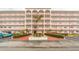 Multi-story condominium building featuring a central entrance with an American flag and well-maintained landscaping at 5501 80Th N St # 207, St Petersburg, FL 33709