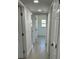 Long hallway with white walls, grey tile flooring, and multiple doorways at 5608 Larimer Dr, Tampa, FL 33615