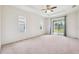 Spacious bedroom offering neutral carpet, ceiling fan, bright windows, and sliding glass doors to the backyard at 6547 Castle Green Pl, Zephyrhills, FL 33541