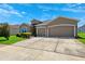 Attractive single-story home boasts a spacious driveway and three-car garage, set against a blue sky backdrop at 6547 Castle Green Pl, Zephyrhills, FL 33541