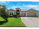 Inviting one-story home featuring a three-car garage, well-maintained lawn, and attractive curb appeal at 6547 Castle Green Pl, Zephyrhills, FL 33541
