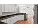 Modern kitchen featuring white cabinets, black countertops, stainless steel appliances, and wood floors at 6547 Castle Green Pl, Zephyrhills, FL 33541