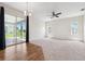Bright living room featuring wood floors, neutral carpet, ceiling fan, and sliding glass doors to the backyard at 6547 Castle Green Pl, Zephyrhills, FL 33541