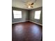 Bedroom featuring a ceiling fan, two windows with blinds, and rich dark wood flooring at 8317 N Marks St # A, Tampa, FL 33604