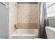 Close-up of a bathtub with light beige tiling, a shower curtain, and gray painted walls at 8317 N Marks St, Tampa, FL 33604