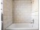 Bathtub featuring light beige tiling, a shower head, and chrome faucet fixtures at 8317 N Marks St, Tampa, FL 33604