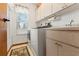 Well-lit laundry room featuring a washer, dryer, cabinets, and a window with blinds at 9202 Jena Rd, Spring Hill, FL 34608