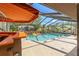 Sparkling screened-in pool features a bar, swan decorations, and a colorful awning at 9202 Jena Rd, Spring Hill, FL 34608